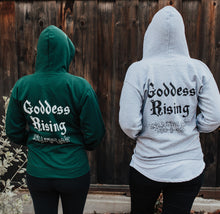 Load image into Gallery viewer, Two people wearing Emerald Hearth hoodies (one in green and one in gray) facing away from the camera.  The hoodies have a spider web detail, the Emerald Hearth Logo, and the words: Goddess Rising.