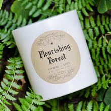 Load image into Gallery viewer, The white Flourishing Forest candle photographed against greenery.