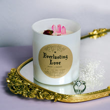 Load image into Gallery viewer, The white Everlasting Love candle with rosebuds around it photographed on top of a mirror with a ring nearby.  This candle is by Emerald Hearth Creations.