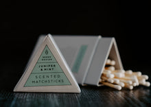 Load image into Gallery viewer, Image of Juniper &amp; Mint scented match sticks.  The lid of the triangle packaging is in the foreground and in focus.  The background is of the matches which is out of focus.