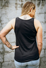 Load image into Gallery viewer, A woman wearing an Emerald Hearth tank top that says Magic Surrounds Me. The woman is standing facing away from the camera and the back of the tank top is blank.