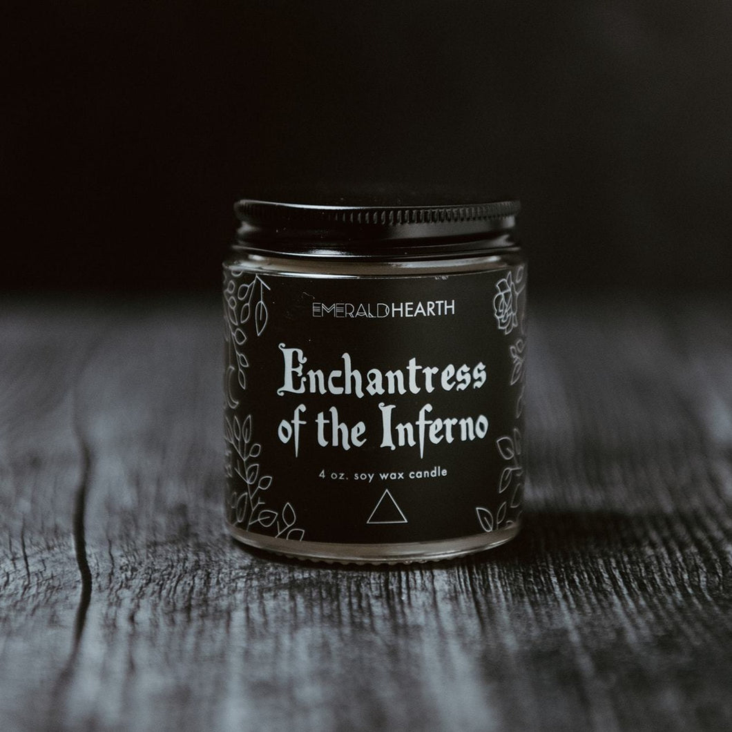 The mini Enchantress of the Inferno candle photographed on wood with a black background.
