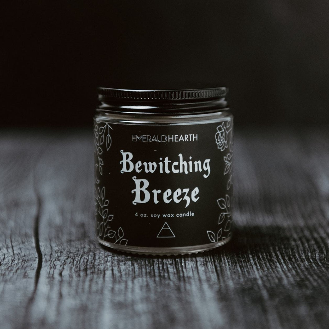Emerald Hearth 4 oz bewitching breeze candle photographed on wood with a black background.