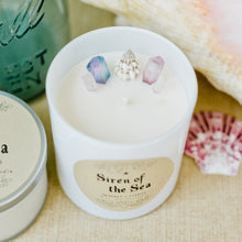 Load image into Gallery viewer, Image of the Siren of the Sea candle by Emerald Hearth.This candle is adorned with titanium-coated, pastel quartz nestled around a seashell to represent the water element.